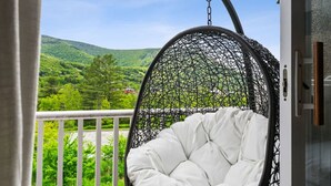 A hanging chair with a white cushion on a balcony with a view of green hills. - Mtn House w/ Hot Tub & Sauna @ Scribners, Sleeps 4 (Tannersville)