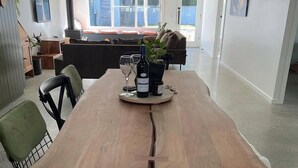 A dining area with a wooden table, chairs, and a bottle of wine. - Premium Halls Gap Holiday Home - Firepit and Local Wine (Halls Gap)