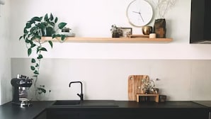 A modern kitchen with a black countertop, a coffee machine, a sink, and bar stools. - Premium Halls Gap Holiday Home - Firepit and Local Wine (Halls Gap)