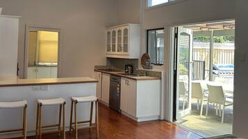 A spacious kitchen with a central island, a dining area with chairs, and a sliding glass door leading to an outdoor patio.