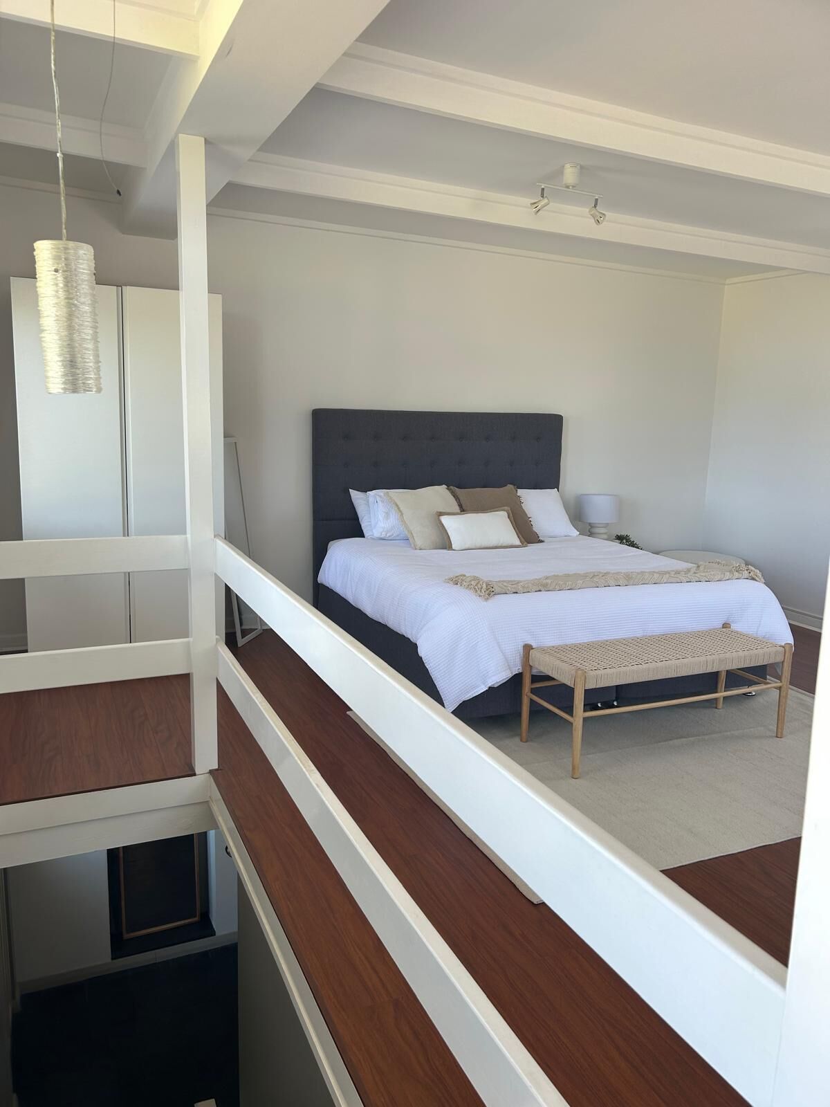 A bedroom with a bed, bedside tables, and a hanging light fixture.
