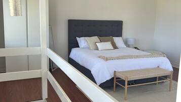 A bedroom with a bed, bedside tables, and a hanging light fixture.