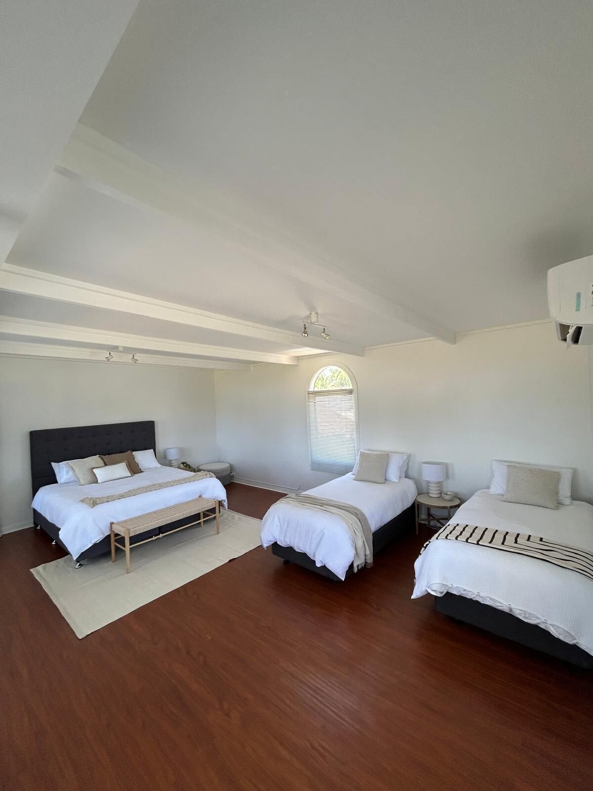A bedroom with two beds, a bench, and a small table.