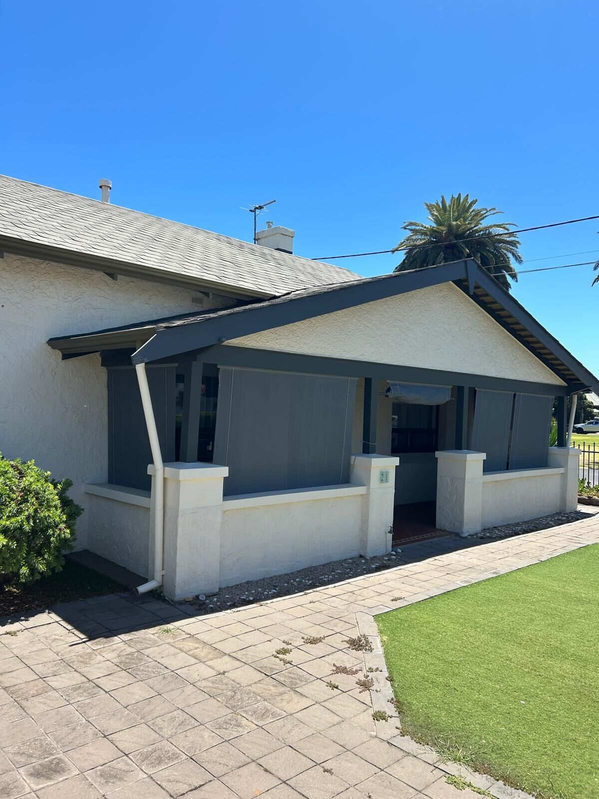 A house with a covered porch, a tiled driveway, and a well-maintained lawn.