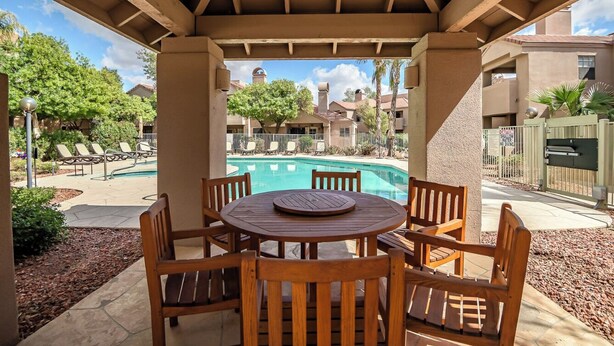 A covered patio area with a pool, wooden chairs, and a table. - Villa Antigua with Resort-Style Pool, Spa, Tennis in Scottsdale Old Town (Scottsdale)