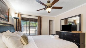 A bedroom with a bed, a ceiling fan, a television on a dresser, and a window with curtains. - Villa Antigua with Resort-Style Pool, Spa, Tennis in Scottsdale Old Town (Scottsdale)