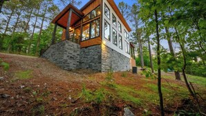A modern house with a stone base, large windows, and a wooden roof. - Mini Marshmallow Cabin - Cozy & Romantic GetAway (Broken Bow)