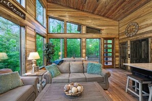 A wooden cabin interior with a sofa, coffee table, and a clock on the wall. - Mini Marshmallow Cabin - Cozy & Romantic GetAway (Broken Bow)