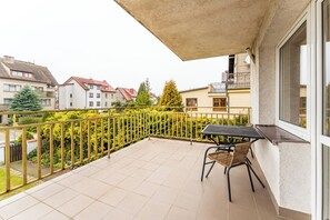 A balcony with a table and chairs, a view of neighboring houses, and a green hedge. - Kołobrzeg Brylantowa Sea Studio #5 (Kołobrzeg)