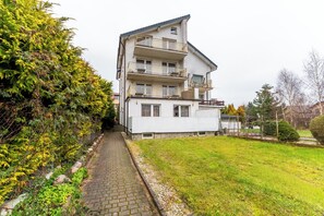 A multi-story residential building with balconies, a paved pathway, and a grassy area. - Kołobrzeg Brylantowa Sea Studio #5 (Kołobrzeg)