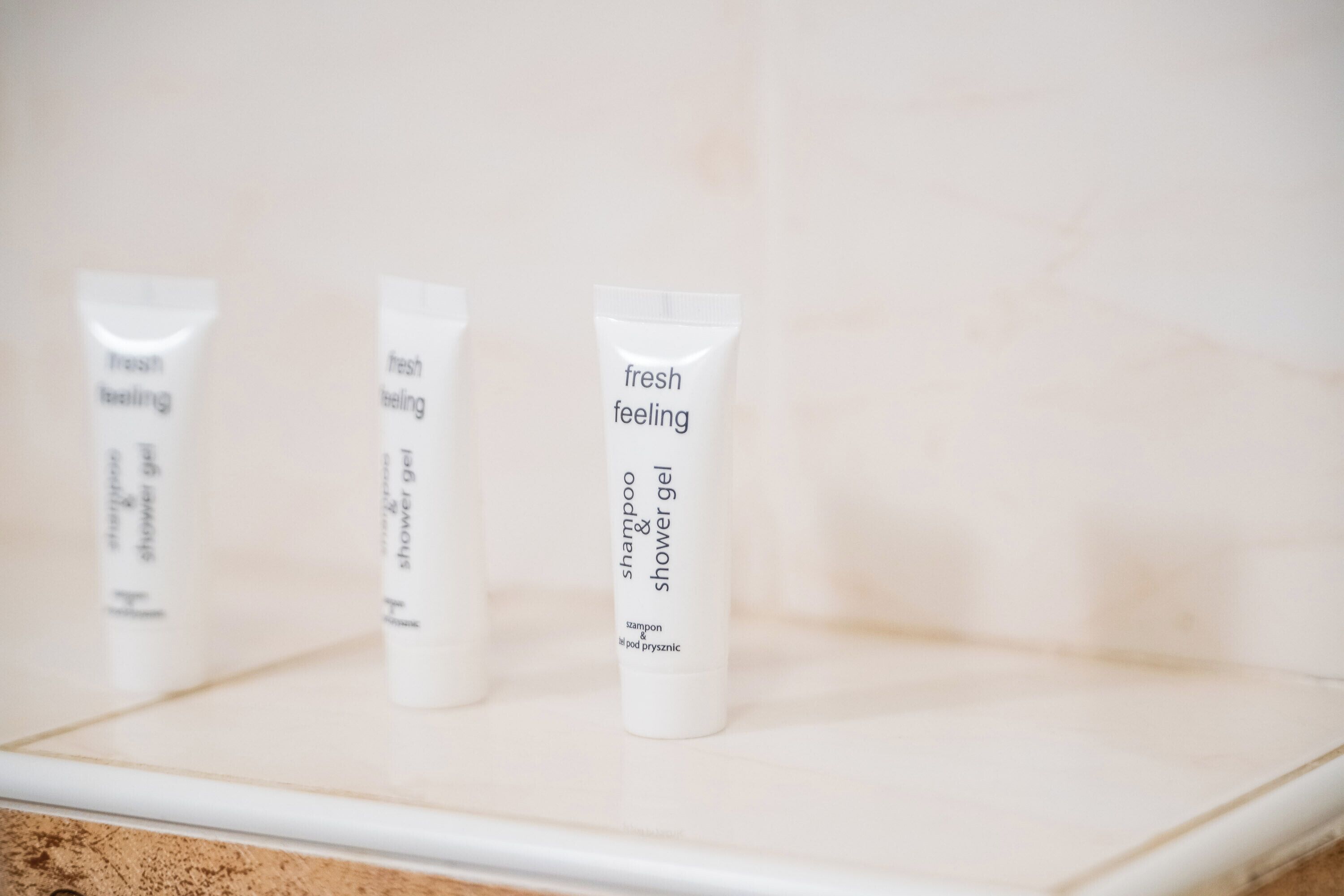 Tres botellas de champú y gel de ducha con aroma fresco sobre un estante blanco.