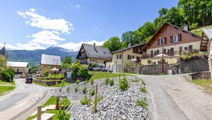 Un pueblo rural con casas tradicionales, una carretera y montañas al fondo.