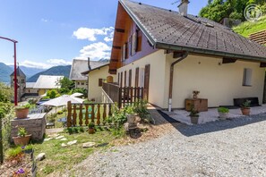 A traditional chalet with a sloped roof, wooden shutters, and a gravel driveway.