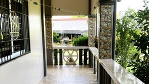 A covered outdoor area with a tiled floor, a railing, and a view of a covered patio with tables and chairs. - Possibly the best private pool in Pampanga - all yours, no sharing (Magalang)