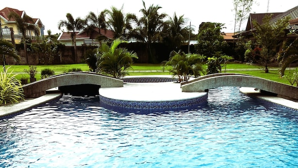 A swimming pool with a stone border and a small bridge. - Possibly the best private pool in Pampanga - all yours, no sharing (Magalang)
