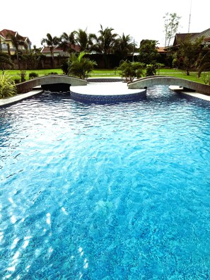 Una piscina con borde de piedra y un pequeño puente.