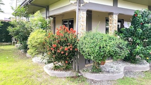 A house with a covered porch, stone pillars, and a garden with various plants and flowers. - Possibly the best private pool in Pampanga - all yours, no sharing (Magalang)