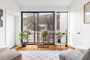 A balcony with a view of trees and buildings, a wooden bench, and two potted plants. - SunRiver Condo Close to BC & Vail - Pet Friendly (Avon)