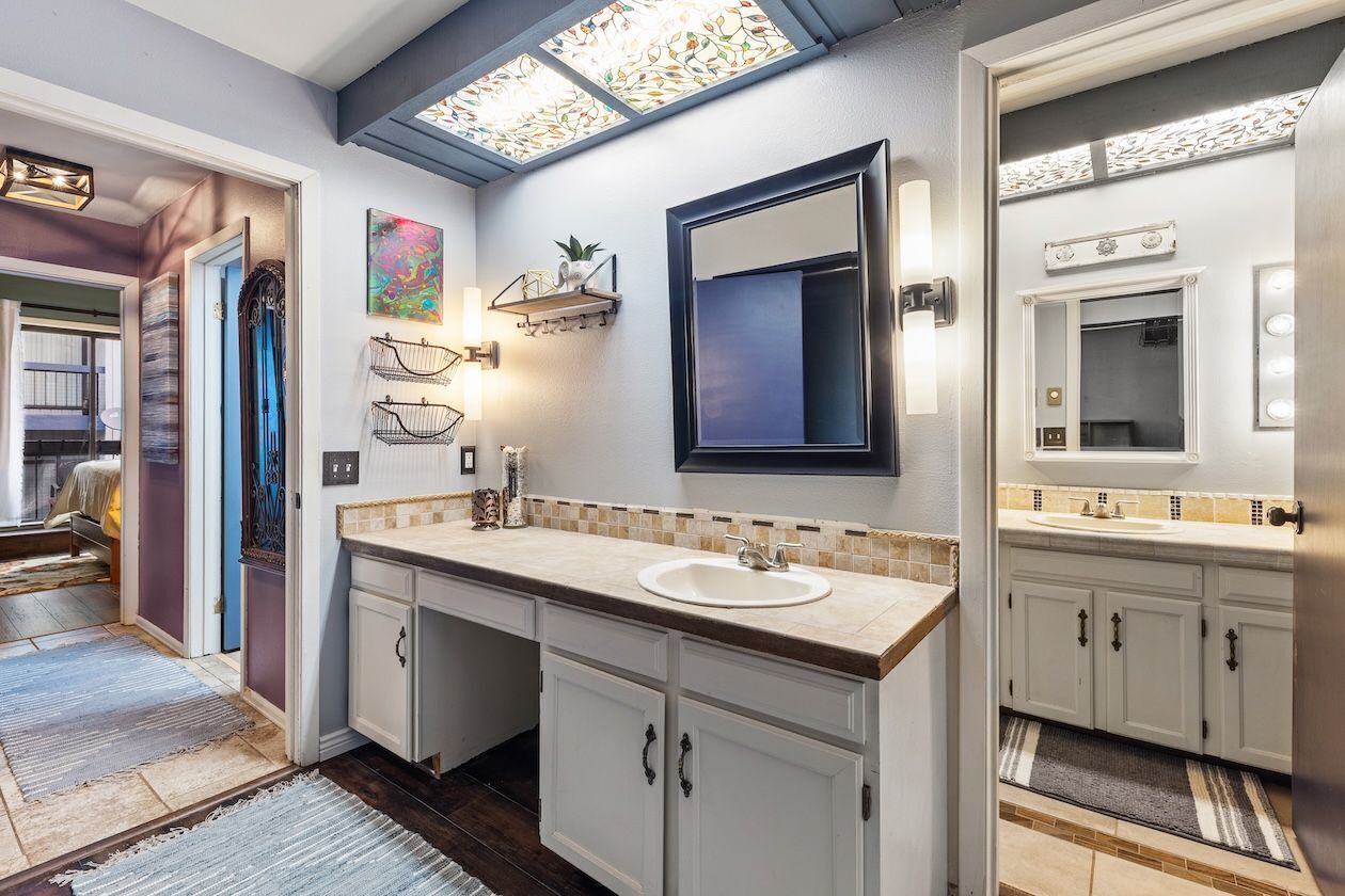 Une salle de bain moderne avec un grand miroir, un lavabo et un meuble-vasque avec des placards.