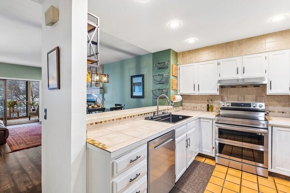 A modern kitchen with white cabinets, a stainless steel oven, and a tiled backsplash. - SunRiver Condo Close to BC & Vail - Pet Friendly (Avon)