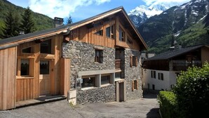 Un edificio de madera con paredes de piedra, ventanas grandes y un balcón.