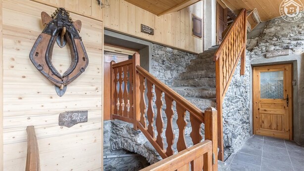 Interior de madera con una escalera de piedra, una puerta de madera y un cartel que dice 'Le Refuge'.