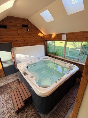 A hot tub in a wooden cabin with a skylight and a window. - The MeadowHouse at Pack Creek Ranch (Moab)