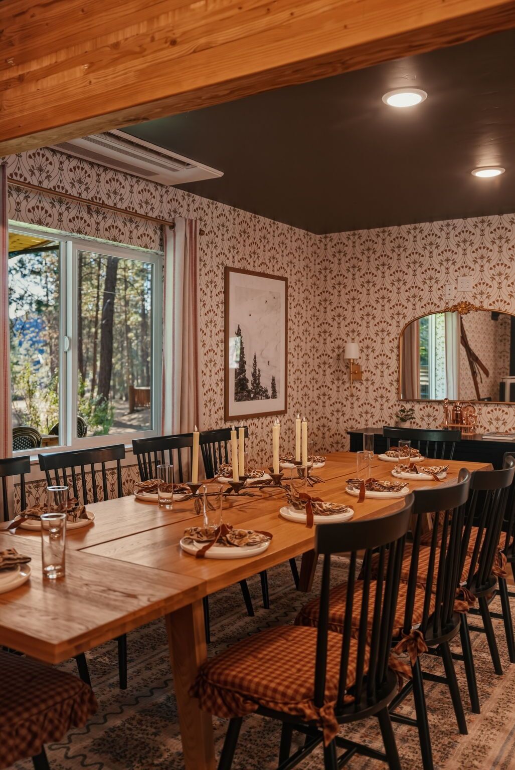 A dining room with a wooden table set for six, surrounded by chairs with checkered cushions.