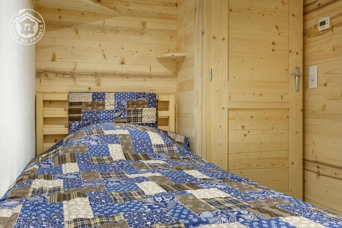Une pièce de style cabane en bois, avec un lit, une porte en bois et un thermostat fixé au mur.