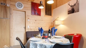 Een eetgedeelte met een ronde tafel gedekt voor vier personen, een klok aan de muur en een schilderij van een hert.