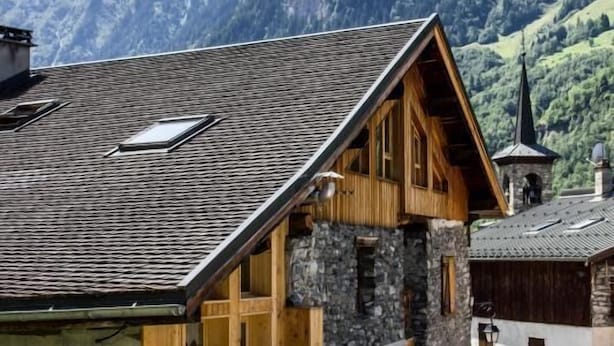Een klassiek chalet met een stenen fundering, houten gevel en een schuin dak.