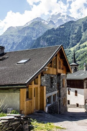 En traditionell chalet med en grund av sten, träfasad och ett sluttande tak.