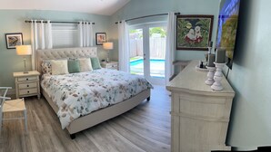 Une chambre à coucher avec un grand lit, une table de chevet, une chaise, une commode et un téléviseur.