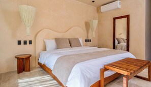 A bedroom with a bed, bedside tables, a wooden bench, a mirror, and an air conditioning unit. - Loch Collection Tulum (Tulum)