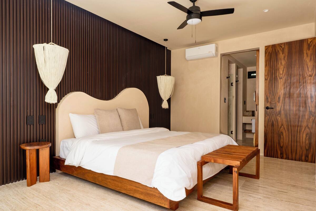 A modern bedroom with a wooden bed, two bedside tables, a ceiling fan, and a wooden wardrobe.