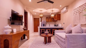 A modern living room with a wooden console table, a round coffee table, a grey sofa, and a TV mounted on the wall. - Loch Collection Tulum  (Tulum)