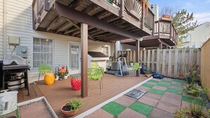 Un patio cubierto con piso de madera, mobiliario exterior y una parrilla.