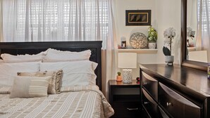 Un dormitorio ordenado con cama, mesitas de noche, cómoda y espejo.