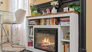 Una chimenea con estanterías arriba y un sillón a la izquierda.