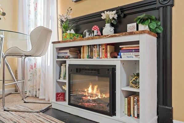 A fireplace with bookshelves above and a chair to the left.