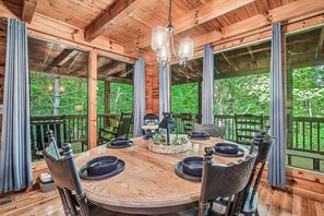 A wooden dining table with chairs, a chandelier, and a view of the outdoors. - Serene Retreat w/ Hot Tub, Deck & Pool Table Between Pigeon Forge & Gatlinburg (Sevierville)