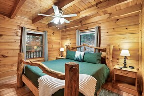 Ein Schlafzimmer einer Holzhütte mit einem Bett, Nachttischen und einem Deckenventilator.