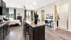 A modern kitchen with a central island, bar stools, a dining area with a sofa, and a small office space. - The Golden Retreat- Mountain Views + Private Patio (Golden)