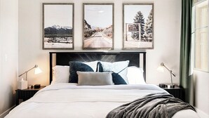 A neatly made bed with a white comforter and pillows, a dark headboard, and three framed pictures above it. - The Golden Retreat- Mountain Views + Private Patio (Golden)