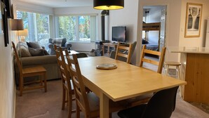 Een gezellige woonkamer met een bank, een eettafel met stoelen, een televisie en een open haard.