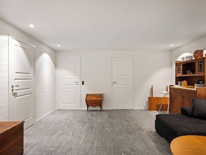 A room with a grey tiled floor, white walls, and a wooden cabinet with various items.