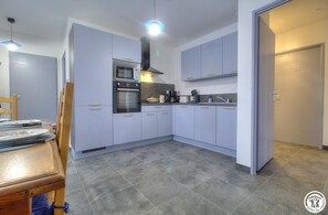 A modern kitchen with grey cabinets, a built-in oven, and a coffee maker. - Gîte de la Clavelle - Coté Azur (SAINT MAURICE DE GOURDANS)