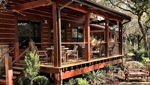 Eine Holzhütte mit überdachter Veranda, Sitzgelegenheiten im Freien und einem Steinweg, der zum Eingang führt.