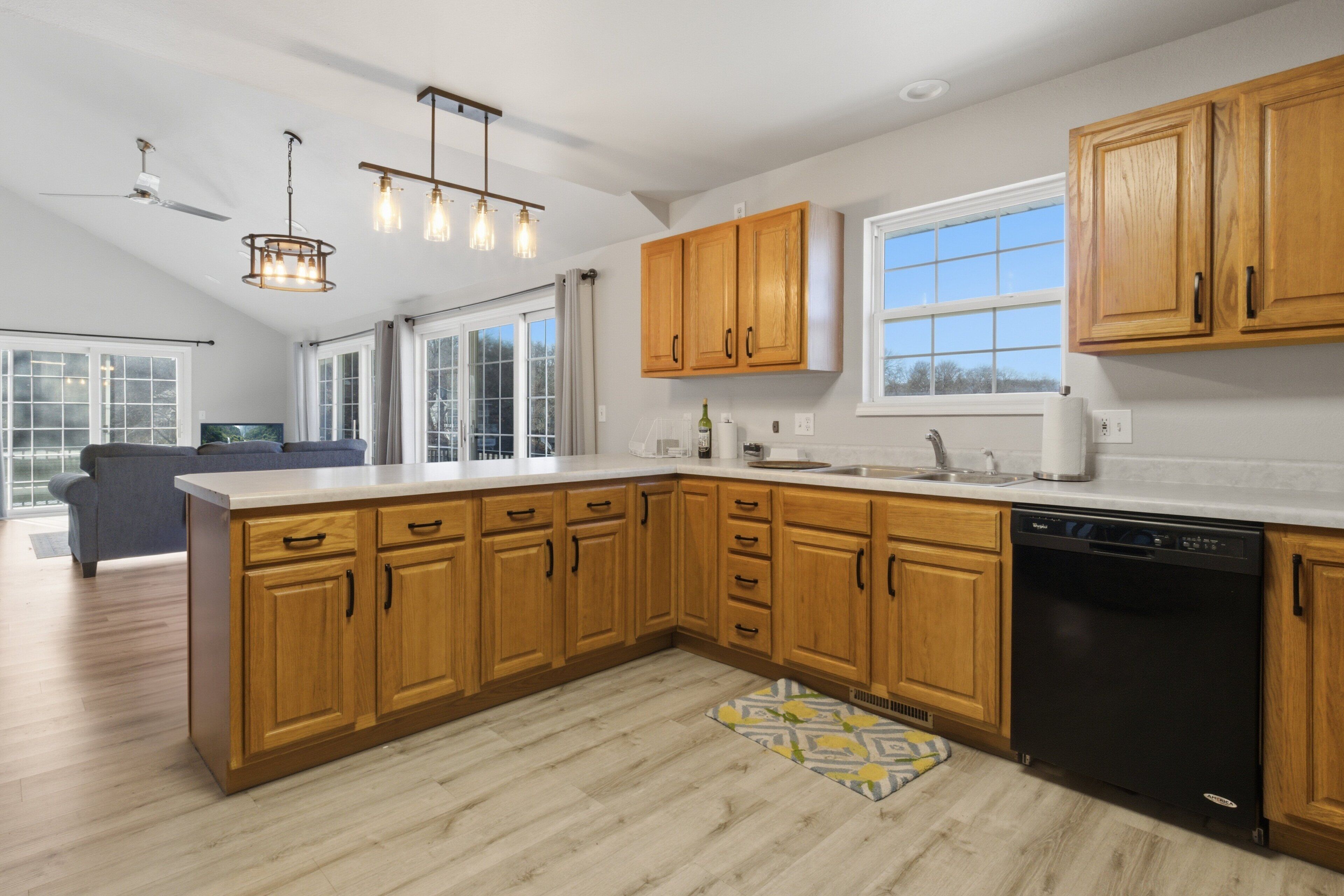 A modern kitchen with wooden cabinets, a dishwasher, and a large window.