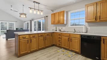A modern kitchen with wooden cabinets, a dishwasher, and a large window.